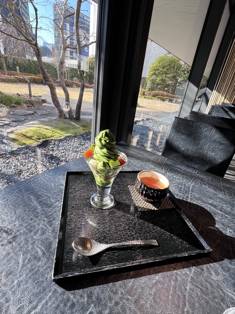 Japanese matcha parfait dessert and tea set served in a modern Tokyo café with garden views.