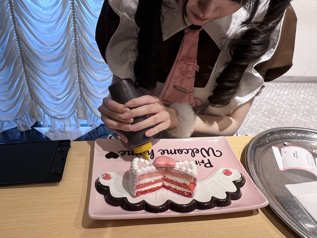Staff member decorating a strawberry shortcake at a maid café in Tokyo, a popular themed dining experience in Japan.