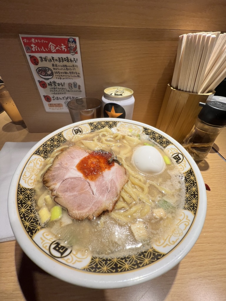 Hearty bowl of Tokyo ramen with chashu pork, egg, and spicy topping served at a local ramen counter in Japan.
