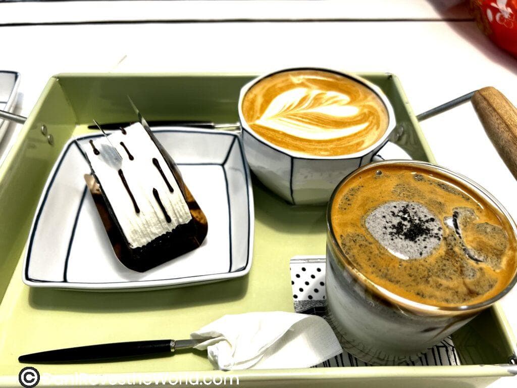 A tray with a slice of cake, a latte with heart-shaped foam art, and an iced coffee served at a stylish café, showcasing the café culture experience in Seoul