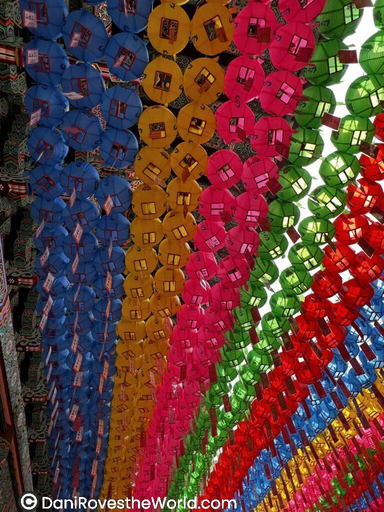 Rows of colorful paper lanterns in blue, yellow, pink, and green, hung in preparation for a festival at Jogyesa Temple in Seoul. These vibrant decorations highlight the festive atmosphere, often seen during events like Buddha's Birthday in spring, which is considered one of the best times to visit Seoul for festivals