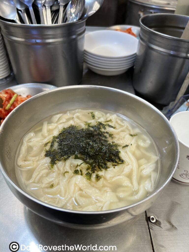 A bowl of kalguksu (Korean knife-cut noodle soup) from the famous Netflix Noodle Queen, topped with dried seaweed, a comforting and must-try dish in Seoul's traditional food scene.