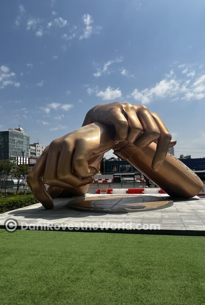 Golden sculpture of hands performing the 'Gangnam Style' dance move, located in Gangnam, Seoul, a famous landmark representing the district's global influence.
