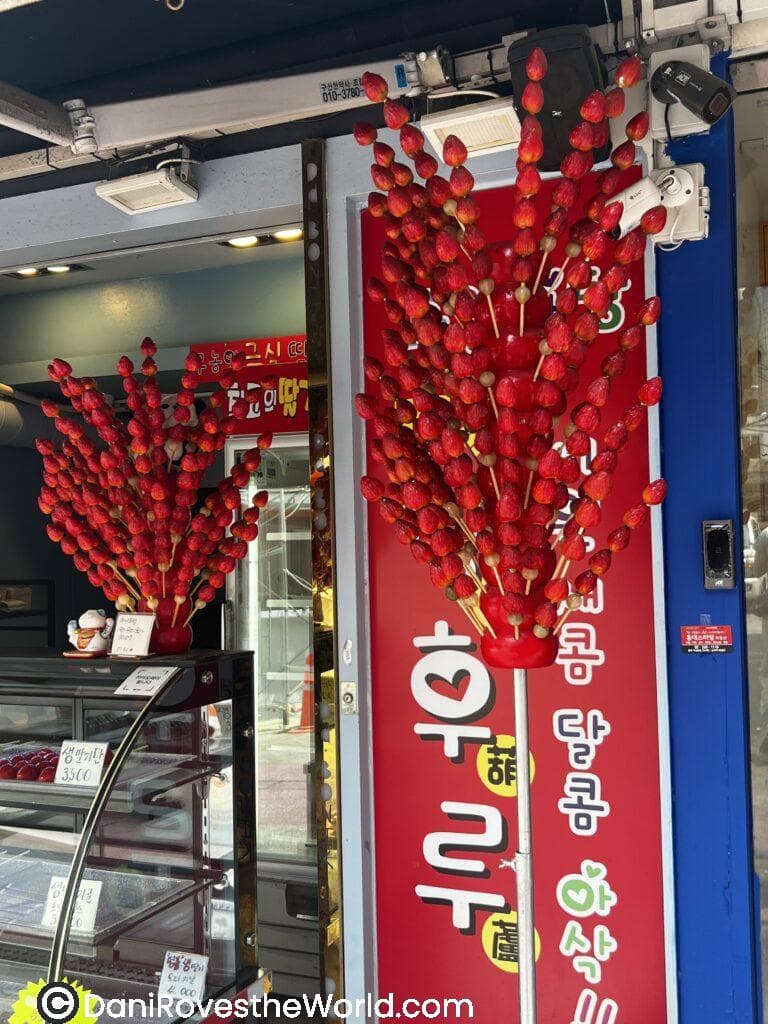 Vibrant display of candied strawberries on skewers outside a shop in Hongdae, Seoul, offering a delicious street food treat for solo female travelers to try