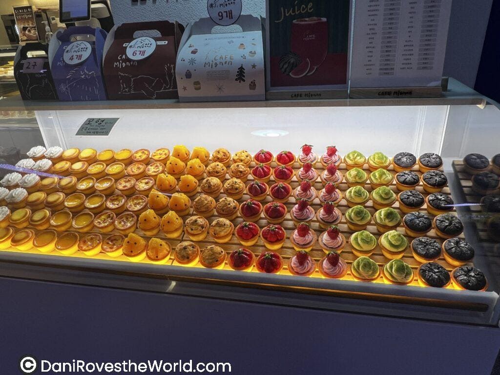 Colorful selection of mini tarts at a bakery in Hongdae, Seoul, featuring flavors like lemon, strawberry, and green tea, a must-try for solo female travelers with a sweet tooth