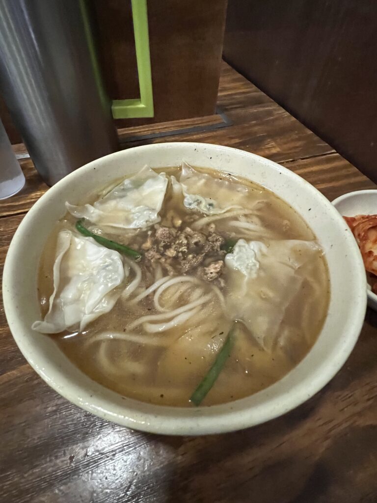 A bowl of flavorful dumpling noodle soup from the Michelin-recognized Myeongdong Kyoja in Seoul, featuring fresh dumplings and savory broth
