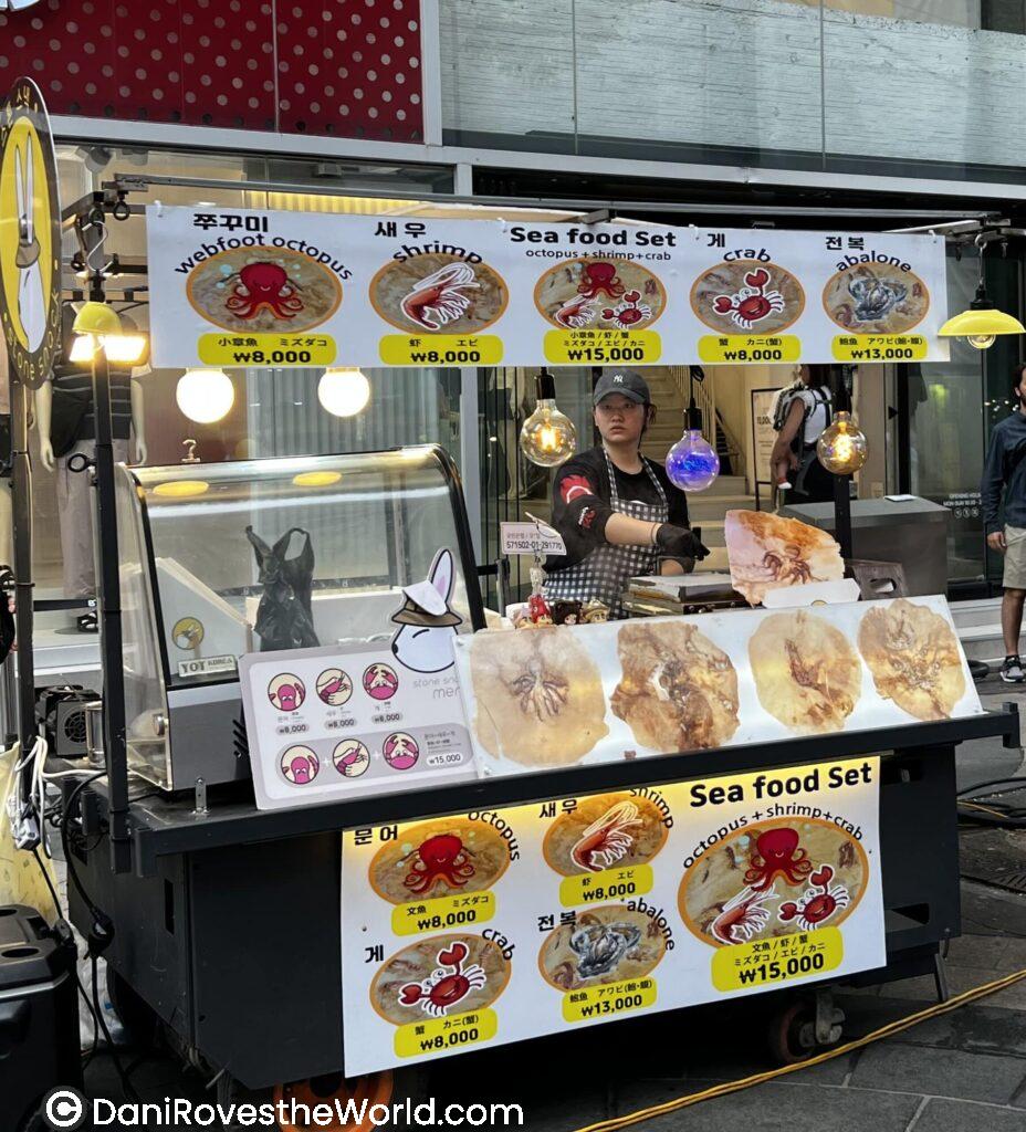 A street food cart offering a seafood set including octopus, shrimp, and crab, showcasing the variety of fresh seafood available during a culinary tour of Seoul.