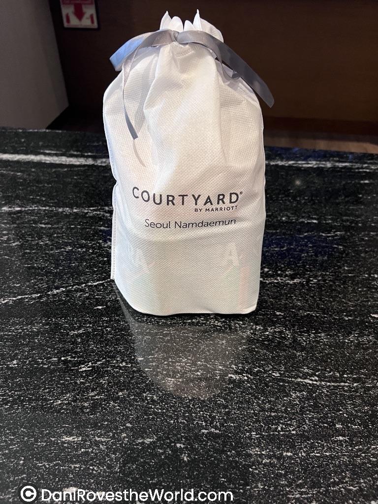 A welcome gift bag from Courtyard Marriott Seoul Namdaemun placed on a counter.