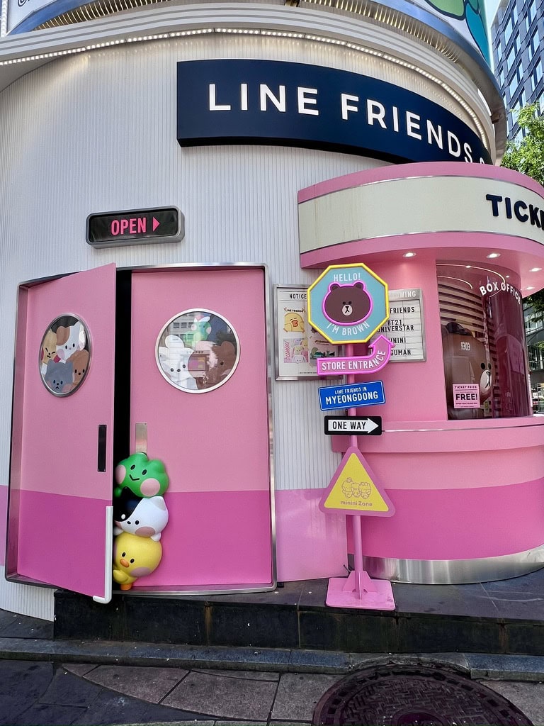 The entrance to the LINE Friends store in Myeongdong, with its signature pink decor and adorable character statues peeking out of the door. Shopping for cute character merchandise here is a must-do activity for fans visiting Myeongdong