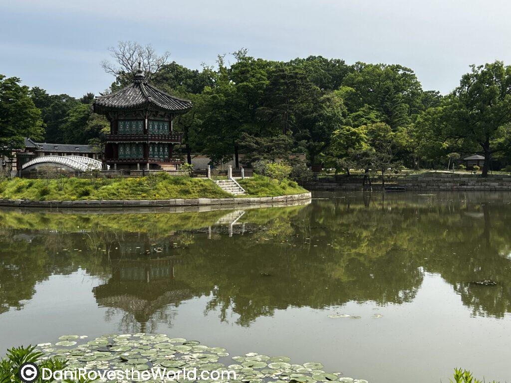 A serene scene at a traditional Korean pagoda reflected in a calm lake, surrounded by lush greenery. Perfect for solo female travelers exploring peaceful spots in Seoul during a 5-day itinerary.
