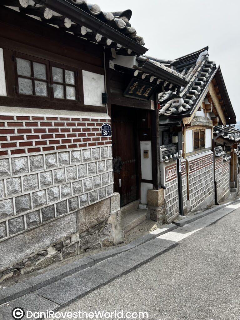 A side view of a traditional Korean house in Bukchon Hanok Village, Seoul, with its tiled roof and stone walls.