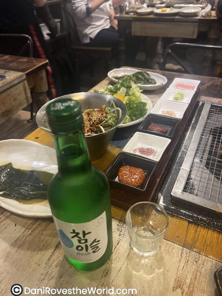 Banchan at a Korean BBQ Restaurant along with Soju. Traditional meal with toppings and sauces