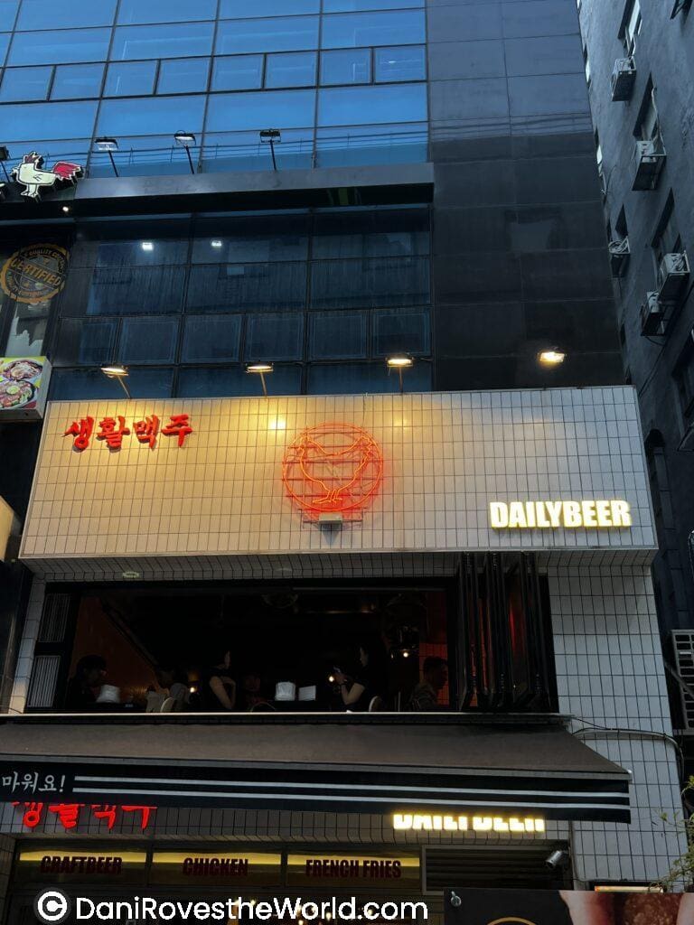 The exterior of Daily Beer, a popular bar in Myeongdong with an open window and neon signage. Enjoying craft beer and snacks at lively venues like Daily Beer is one of the fun things to do in Myeongdong for a night out.