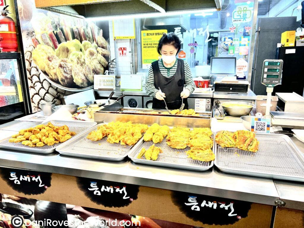 A street food vendor preparing various fried Korean snacks at a Mangwon market in Seoul.