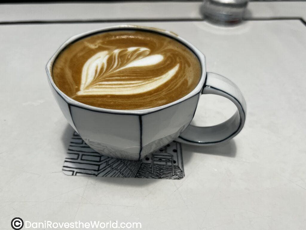 A cup of coffee with intricate latte art served in a minimalist café in Seoul. Solo female travelers can relax in Seoul’s stylish cafes