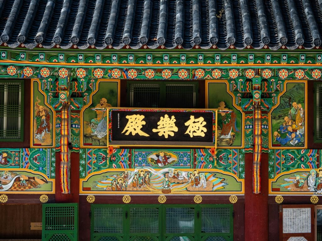 Ornate mural and calligraphy on the facade of Jogyesa Temple, illustrating traditional Korean Buddhist art and storytelling.