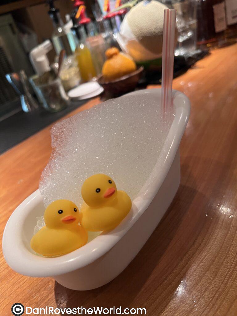 A cocktail in a mini bath tub with two rubber ducks and bubbles from Orchard Bard in Tokyo. 