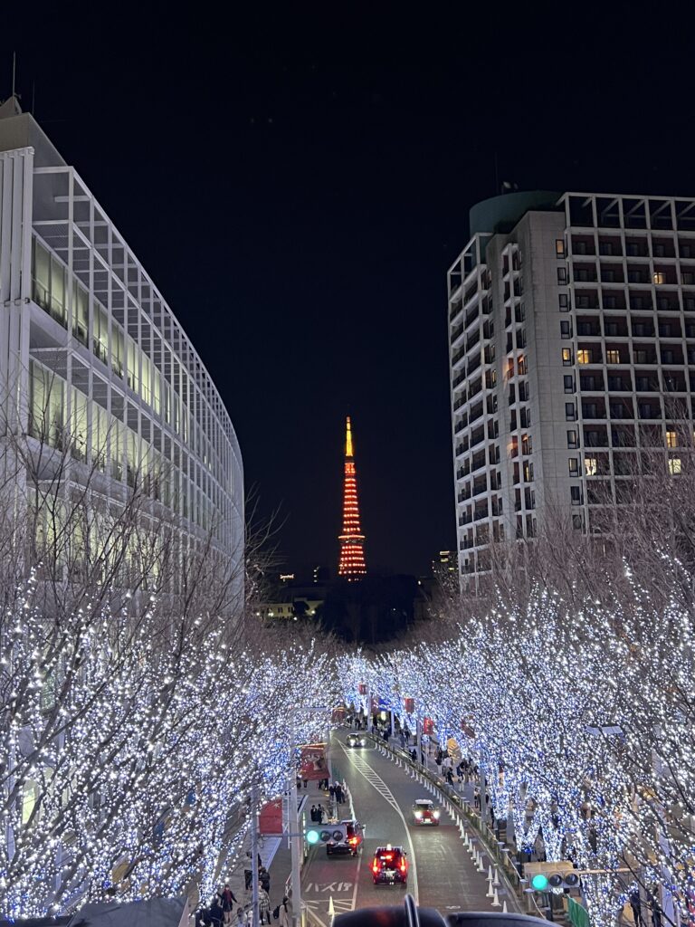 Tokyo Tower glowing orange at night beyond a street lined with sparkling winter lights in Roppongi, a festive neighborhood for where to stay in Tokyo.