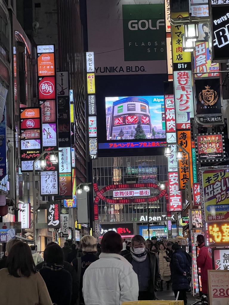 Bustling night street scene in Tokyo’s Kabukicho district, packed with glowing izakaya signs, crowds of people, and neon lights—capturing the energy of a Tokyo izakaya tour.
