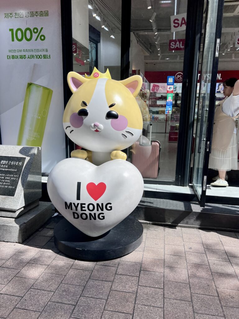 Cute cat statue holding an “I Love Myeongdong” heart sign outside a cosmetics store in the Myeongdong shopping district in Seoul.
