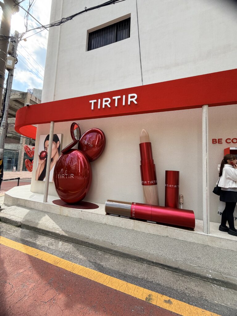 TIRTIR beauty store exterior in Seoul with oversized makeup displays and bold red branding.